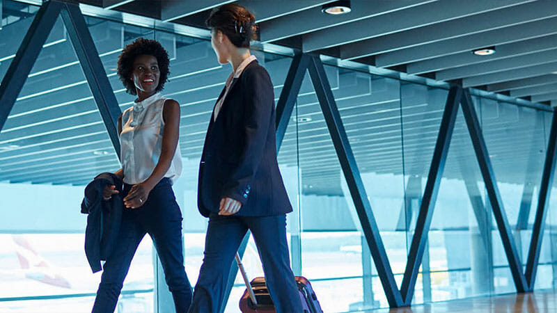 Two women talking and walking at the airport